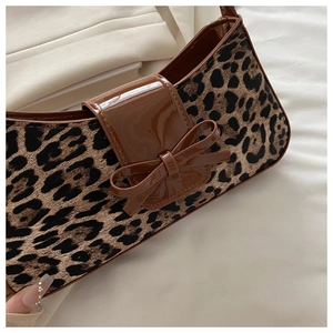 Detail of leopard print fabric bag featuring brown patent leather flap and bow decoration