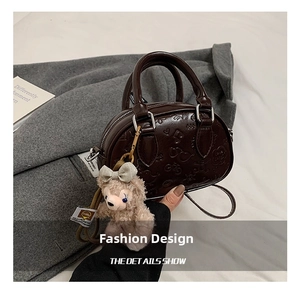 Détail du sac marron en similicuir avec gaufrage de dessins animés et charm en peluche