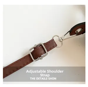 Detail of adjustable brown leather shoulder strap with silver metal buckle and clasp