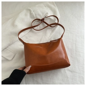 Detailed close-up of brown vintage leather tote with adjustable strap on white fabric