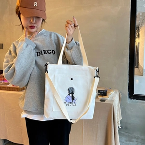 Detailed shot of white canvas tote bag with black cartoon print and large front pocket