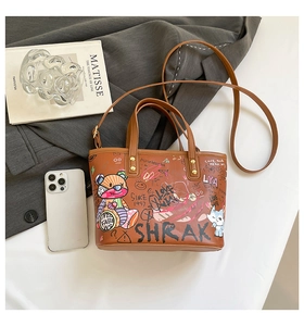 Détail d'un sac cabas marron avec graffitis, motifs de dessins animés et bandoulière