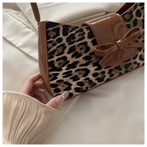 Detail of leopard print shoulder bag featuring patent leather trim and bow decoration
