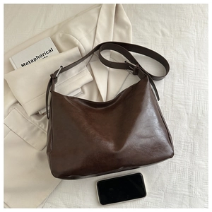 Détail d'un sac cabas en cuir PU marron foncé avec boucle argentée et texture lisse