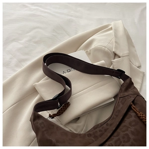 Detail of leopard print crossbody bag featuring a wide strap and woven zipper puller