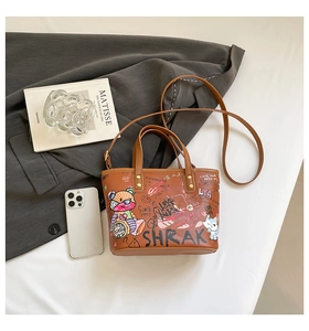 Détail du sac cabas marron à imprimé graffiti avec bandoulière sur blazer gris
