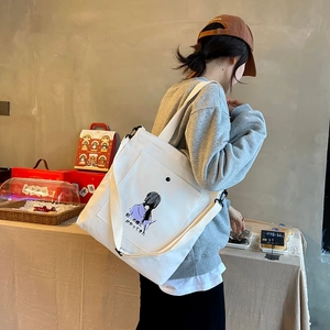 Detail of white canvas tote bag featuring purple anime illustration and shoulder strap