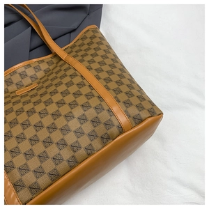 Detail of brown printed tote bag showing vintage geometric patterns and leather handles