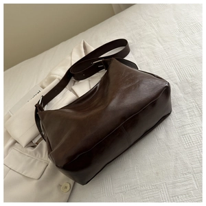 Détail d'un grand sac à bandoulière marron foncé texture huilée sur fond blanc épuré