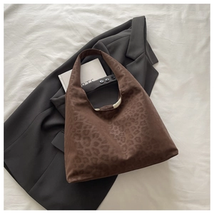 Detail of vintage leopard print tote bag placed on a grey blazer over white fabric