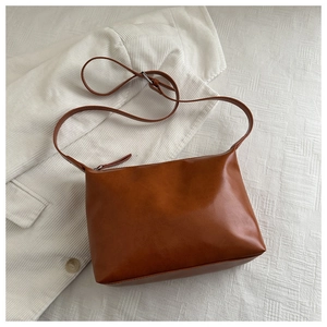 Detail shot of brown faux leather tote bag with smooth texture and adjustable strap