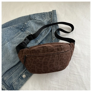 Detail of leopard print crossbody bag on denim jacket showing fabric texture and strap