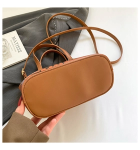 Détail du sac bandoulière en cuir caramel avec lettrage artistique et bandoulière réglable