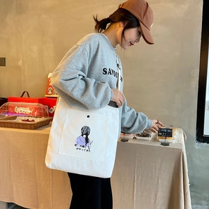 Close-up of white canvas tote bag with anime illustration in a cozy cafe setting