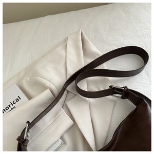Détail d'un sac cabas en cuir marron foncé avec bandoulière réglable et boucle en métal