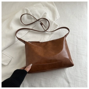 Close-up of brown retro faux leather tote bag with adjustable strap and stitching detail