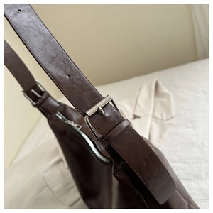 Détail de la boucle argentée ajustable et texture en cuir vintage sur un sac fourre-tout