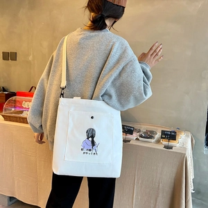 Detail of white canvas crossbody bag featuring girl illustration and adjustable strap