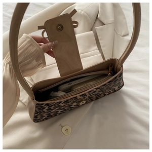 Macro view of leopard print baguette bag interior with magnetic clasp and zip pocket