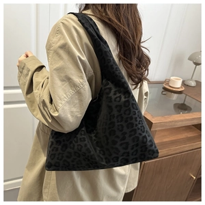 Detail view of black leopard print tote bag on shoulder with autumn trench coat