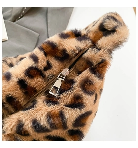 Close-up of leopard faux fur texture and smooth golden metal zipper on the bag