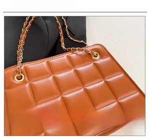 Close-up of brown quilted leather texture and gold chain strap on the flap bag