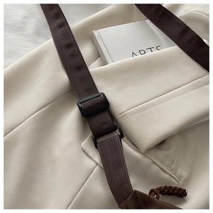 Detail of beige canvas crossbody bag with brown nylon strap and adjustable black buckle