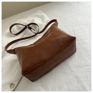 Detail view of brown vintage leather bag with adjustable strap and neat stitching texture