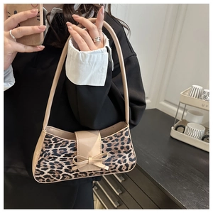Detail of leopard print faux fur texture with beige patent leather bow on shoulder bag