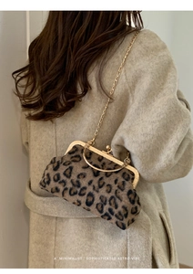 Detail of leopard print shell bag with golden metal handle and fine chain strap worn by model