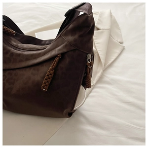 Close-up of leopard print shoulder bag featuring a woven zipper pull and side pocket