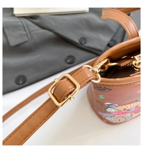 Gros plan sur les boucles dorées et la bandoulière en cuir réglable du sac imprimé