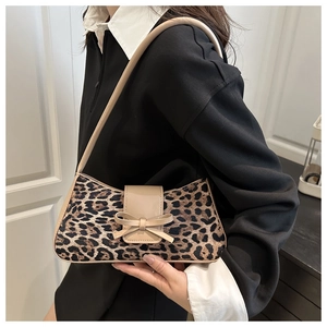 Detail shot of leopard print shoulder bag with cream bow accent and glossy leather strap