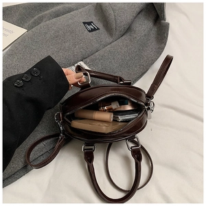 Détails de la capacité intérieure du sac rond en cuir marron avec objets du quotidien