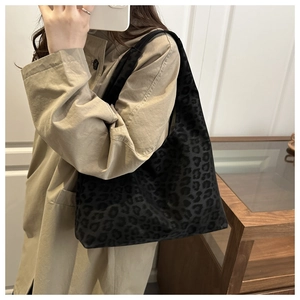 Close-up of leopard print hobo bag worn by model in a stylish long khaki trench coat