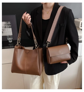 Detail of dark brown leather tote bag and crossbody set worn by a model in a suit