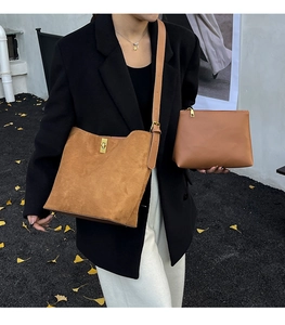 Détail du sac seau en daim marron avec fermoir métallique et pochette assortie