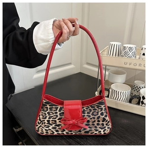 Detail of red patent leather bow and leopard print texture on the handbag flap