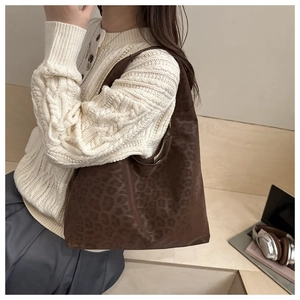 Close-up of leopard print tote bag styled with white sweater for autumn fashion