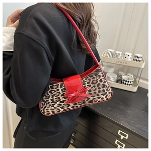 Detail view of leopard print shoulder bag with red lacquer bow and shoulder strap