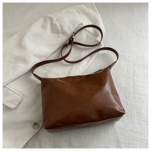 Detail showing matte texture and adjustable strap of brown leather tote bag