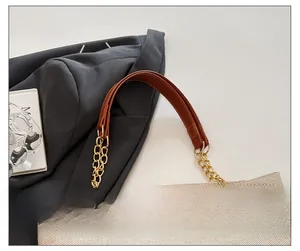 Detail of beige woven tote bag with chain strap, leather handle and metal deer charm