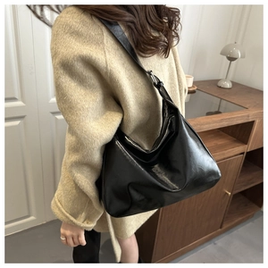 Détail du sac hobo noir brillant montrant la boucle métallique argentée sur la bandoulière