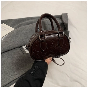 Détail du mini sac bandoulière marron foncé avec motifs de cœurs et fleurs en relief