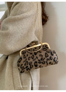 Detail of leopard print plush shell bag with gold clasp and chain on model in beige coat