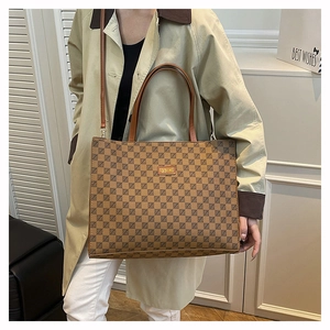 Close-up of the vintage brown checkered tote bag with gold metal plaque and leather strap
