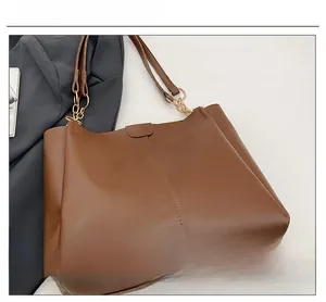Close-up of brown faux leather tote bag with metallic chain and detailed stitching