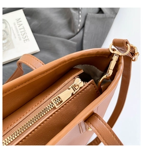 Détail de la fermeture éclair dorée et coutures sur un sac cabas en cuir marron
