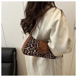 Detail of leopard print shoulder bag with brown faux leather trim and bow accent on model