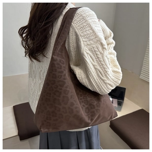Detailed back view of a stylish leopard print tote bag worn on shoulder in a cozy setting